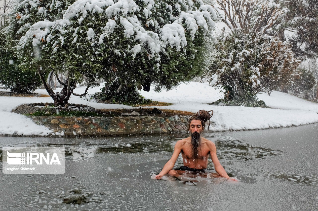 (عکس) تصویری عجیب از شنای جوان تهرانی در حوضچه یخ‌زده پارک!