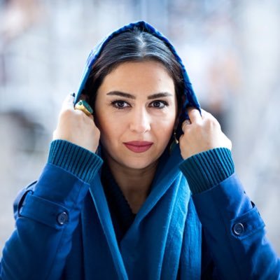 تینا پاکروان در حال درست کردن روسری سرمه ای رنگش به دوربین نگاه کرده است
