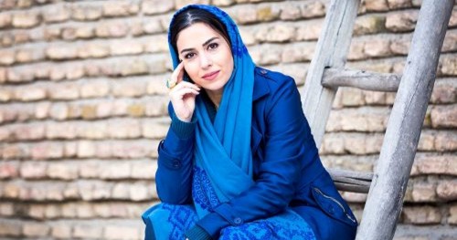 تینا پاکروان با لباس و روسری آبی بر پله نردبان نشسته است