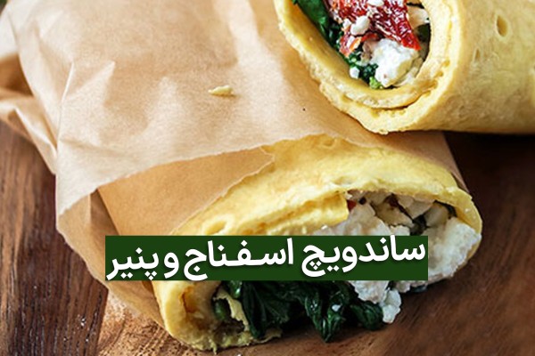 ساندویچ اسفناج و پنیر در نان لواش بر میز چوبی قهوه ای رنگ با عکس نوشته آن