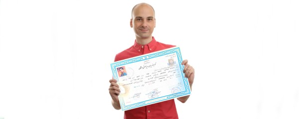 A replica of a diploma and pre-university degree is placed in the hand of a young boy facing the camera