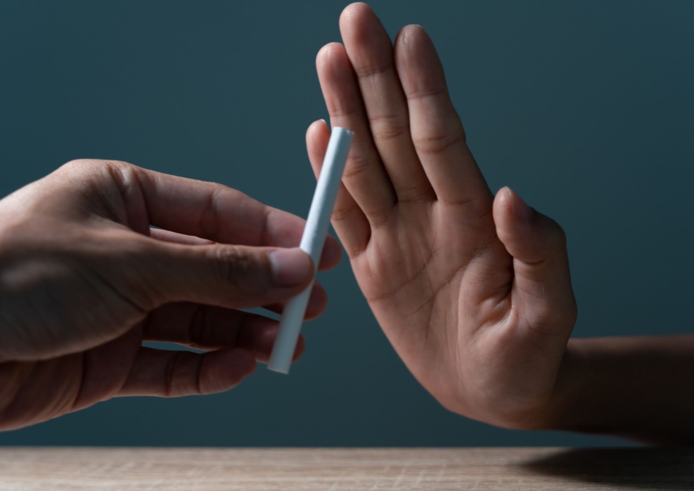 A person's hand giving a cigarette to another personDescription